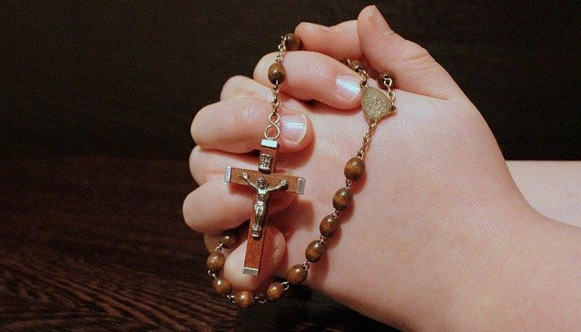 Someone's hands clasping a rosary