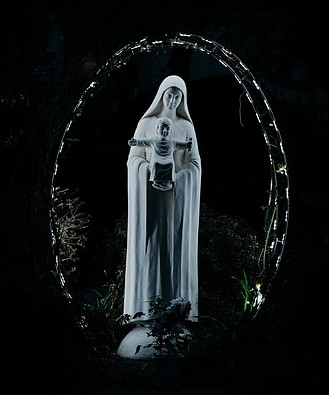 A white statue of Mary holding Christ against a dark background.