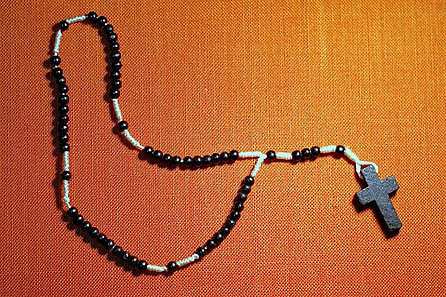 A wooden rosary with black beads and a simple wooden cross at the end