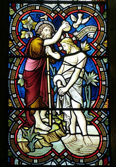 A stained glass window icon of Christ's being baptised