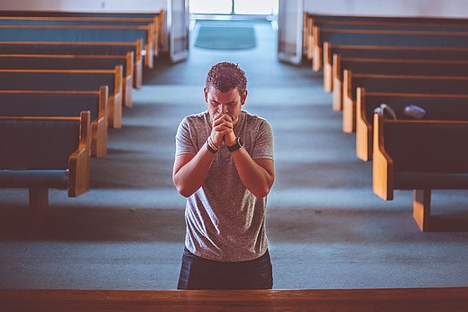 A man on his knees in church praying with passion