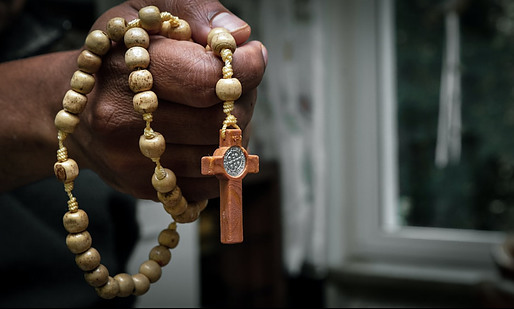 A hand holding a wooden rosary