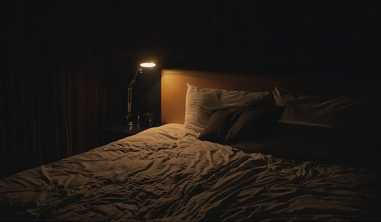 A bed in the dark, with a little light on