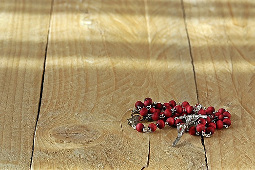 A red rosary on a wooden table