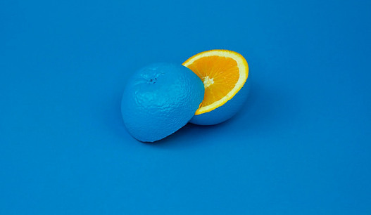 A blue painted Orange, cut in half, against a blue backdrop