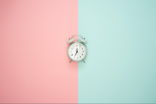 A clock against a pink and blue backdrop